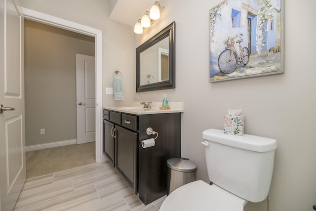 bathroom with baseboards, toilet, and vanity