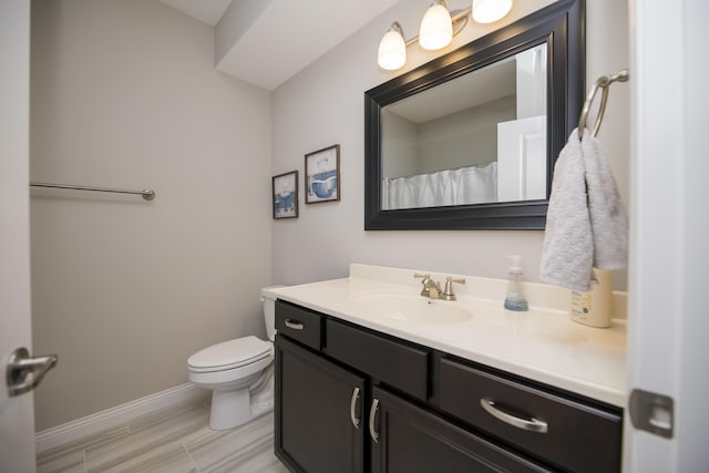 bathroom featuring vanity, toilet, and baseboards