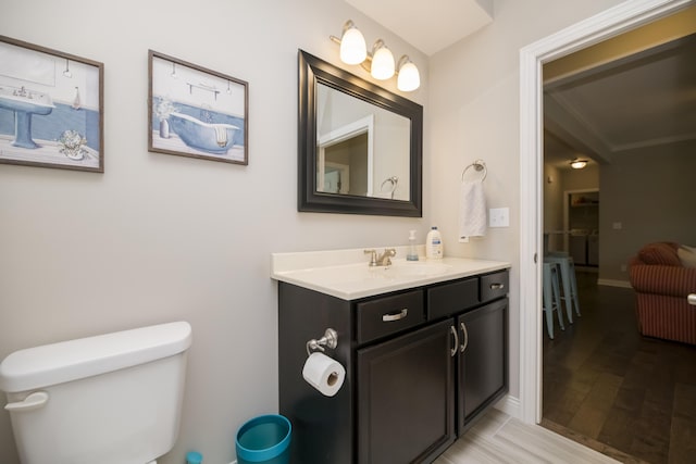 bathroom with toilet, vanity, baseboards, and wood finished floors