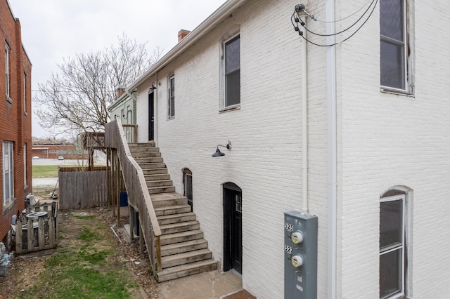 view of home's exterior featuring brick siding, a chimney, and stairs