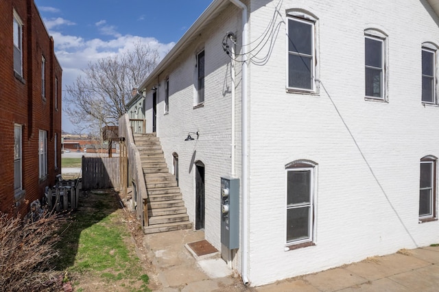 view of property exterior featuring stairway and brick siding