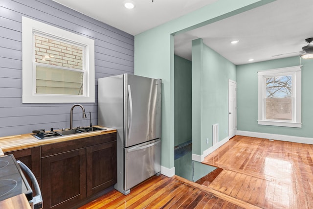 kitchen featuring visible vents, electric range oven, freestanding refrigerator, dark brown cabinetry, and light wood finished floors