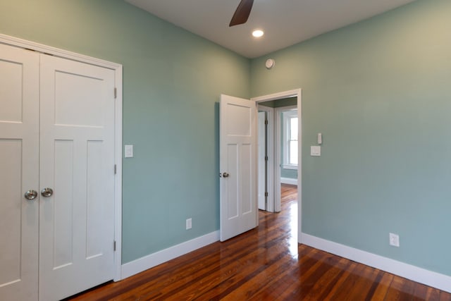 unfurnished bedroom featuring a closet, baseboards, wood finished floors, and a ceiling fan