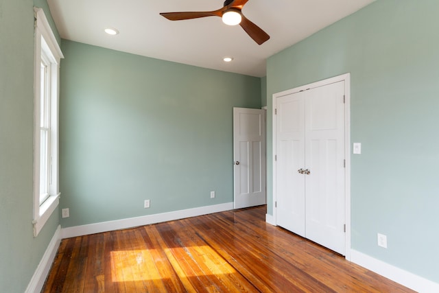 unfurnished bedroom featuring hardwood / wood-style flooring, a ceiling fan, baseboards, and a closet