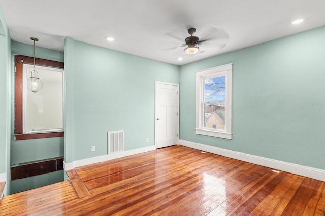 spare room featuring visible vents, ceiling fan, baseboards, and hardwood / wood-style flooring