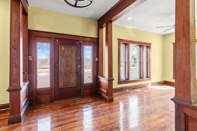 foyer with ceiling fan, baseboards, wood finished floors, and ornate columns