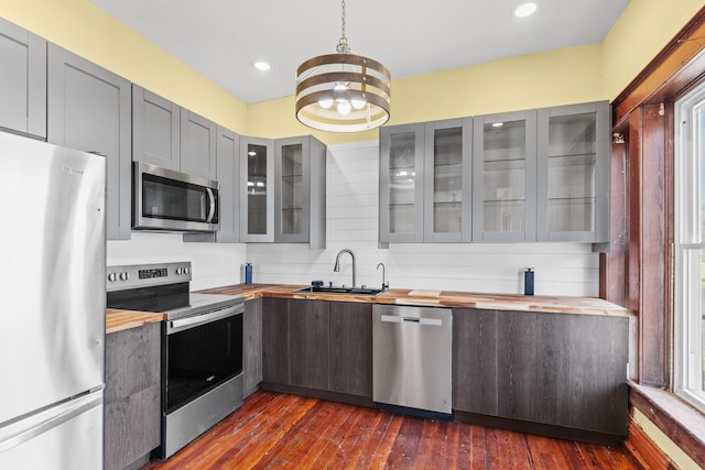 kitchen with a sink, butcher block countertops, gray cabinets, and stainless steel appliances