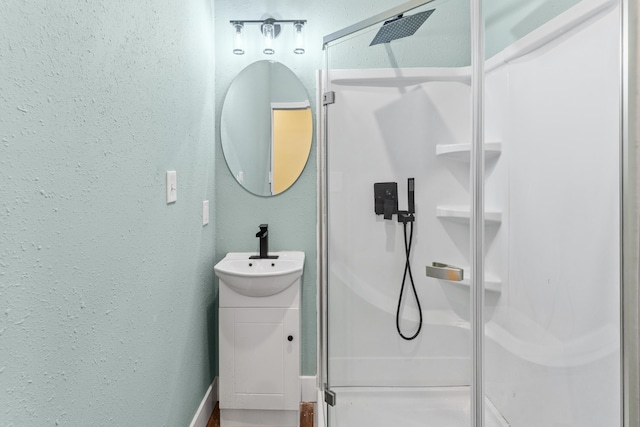 full bathroom featuring a stall shower, vanity, and a textured wall