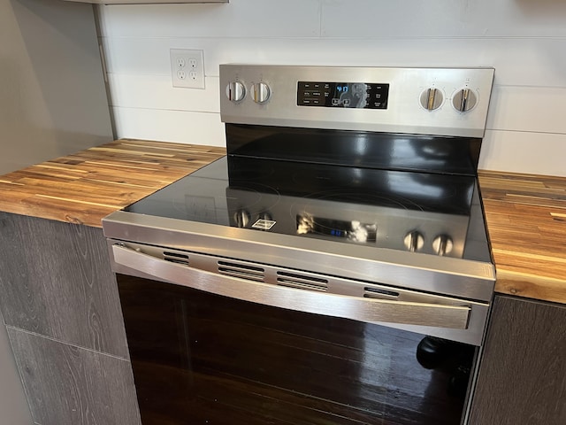 interior details with stainless steel electric stove and wooden counters