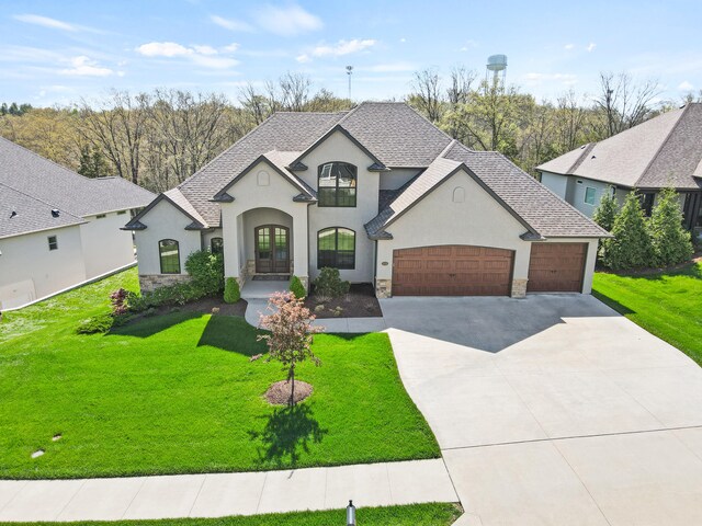 french country home featuring driveway, stone siding, an attached garage, stucco siding, and french doors