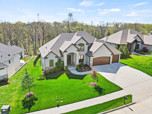 french country inspired facade featuring a shingled roof, stucco siding, driveway, stone siding, and an attached garage