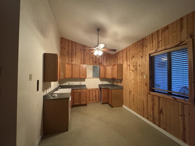 6112 E Forsee Rd, Ashland, MO 65010 - kitchen featuring a ceiling fan, dark countertops, wood walls, vaulted ceiling, and brown cabinets