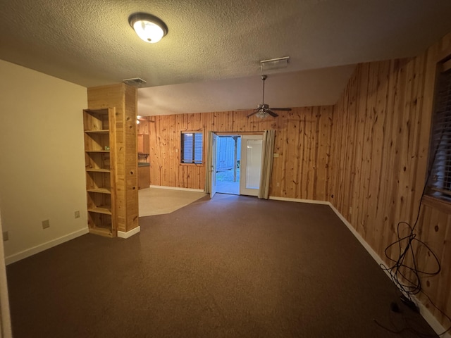 6112 E Forsee Rd, Ashland, MO 65010 - unfurnished room featuring wood walls, baseboards, a textured ceiling, a ceiling fan, and dark carpet