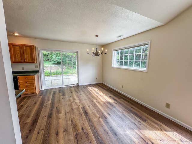 6132 E Forsee Rd, Ashland, MO 65010 - unfurnished dining area with a textured ceiling, visible vents, baseboards, dark wood-type flooring, and a chandelier