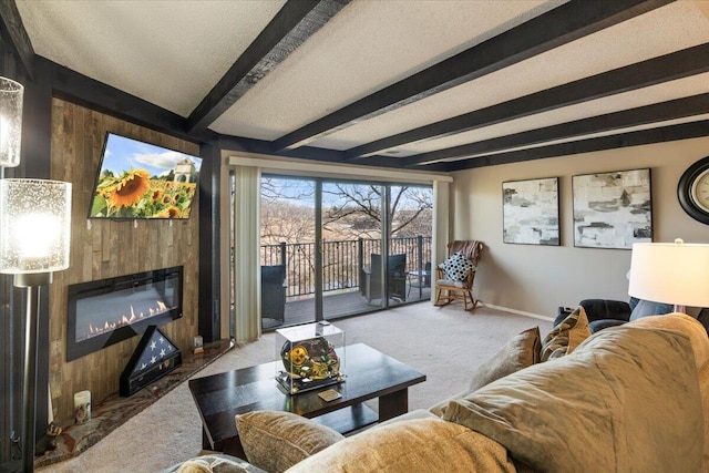 carpeted living room featuring a textured ceiling, a large fireplace, wooden walls, baseboards, and beam ceiling
