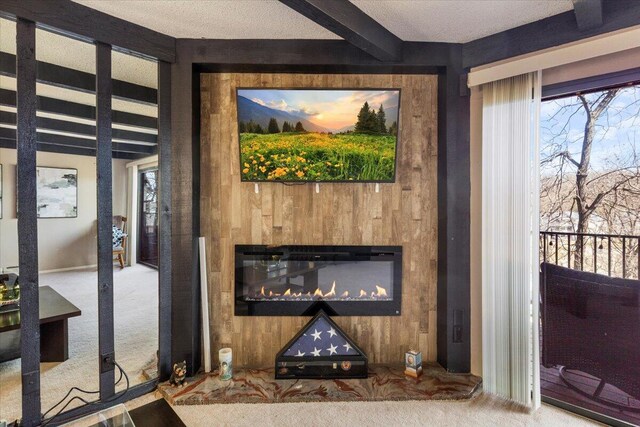 interior details with carpet flooring, a textured ceiling, wooden walls, beam ceiling, and a glass covered fireplace