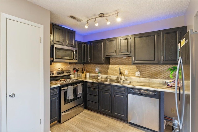 kitchen with light countertops, a sink, light wood finished floors, appliances with stainless steel finishes, and visible vents