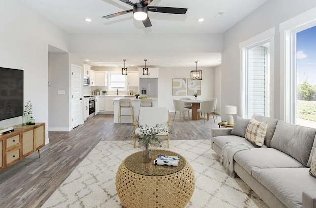 living room with baseboards, wood finished floors, recessed lighting, and a ceiling fan