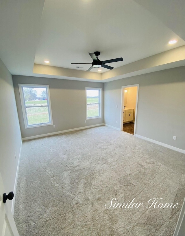 unfurnished bedroom with carpet flooring, a ceiling fan, a raised ceiling, baseboards, and recessed lighting