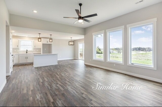 unfurnished living room featuring visible vents, baseboards, ceiling fan, wood finished floors, and a sink