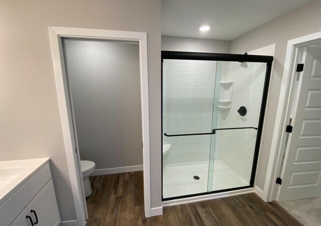 full bathroom with toilet, vanity, a shower stall, wood finished floors, and baseboards