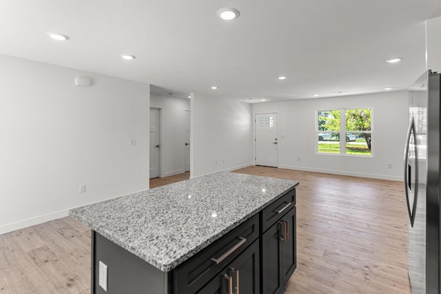 35 Andy Ct, Clark, MO 65243 - kitchen with freestanding refrigerator, a center island, recessed lighting, light wood-type flooring, and light stone counters