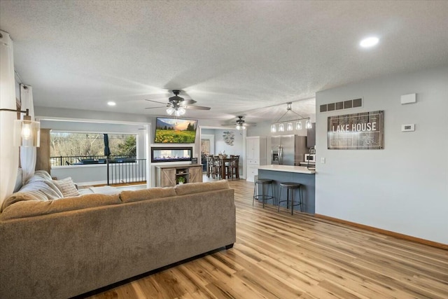 28489 Possum Trot Rd, Stover, MO 65078 - living area with a textured ceiling, light wood-style flooring, baseboards, and a ceiling fan
