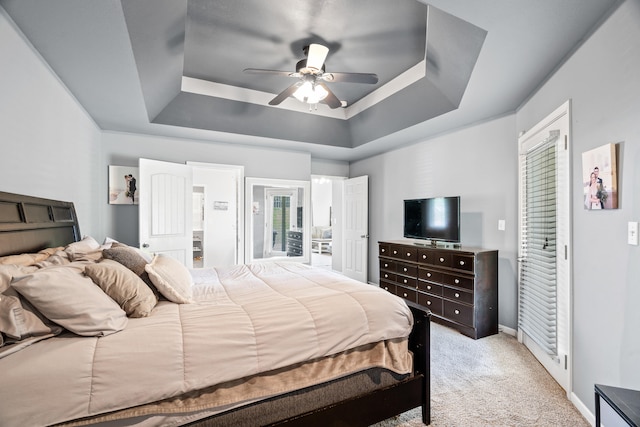 bedroom with baseboards, a ceiling fan, a tray ceiling, and light colored carpet