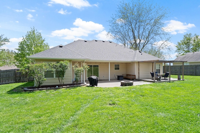 back of house featuring roof with shingles, a fenced backyard, an outdoor fire pit, a yard, and a patio