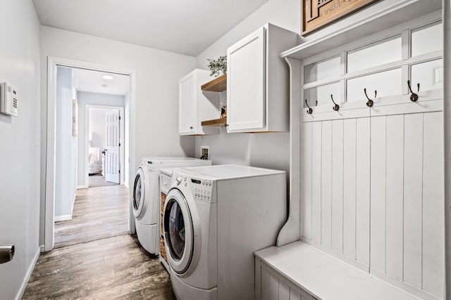 clothes washing area featuring baseboards, light wood-style flooring, cabinet space, and independent washer and dryer