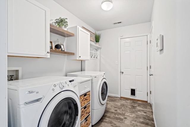 washroom with wood finished floors, visible vents, cabinet space, and washer and clothes dryer