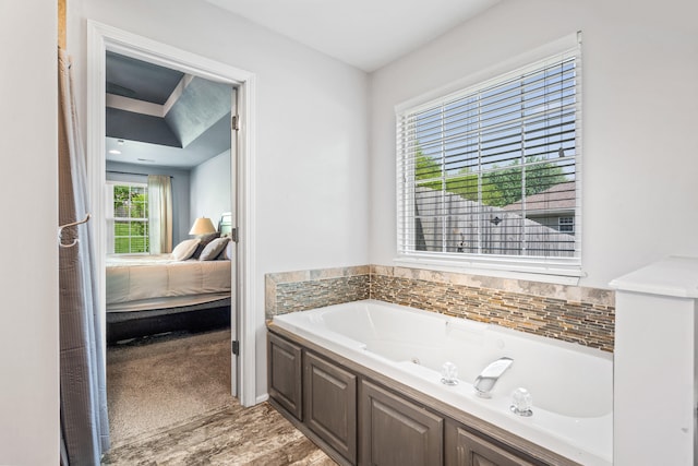 ensuite bathroom with connected bathroom, a tub with jets, and wood finished floors