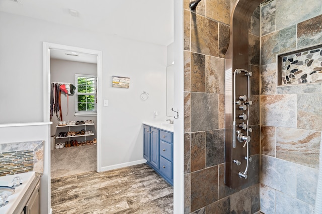 full bathroom featuring vanity, a tile shower, and wood finished floors