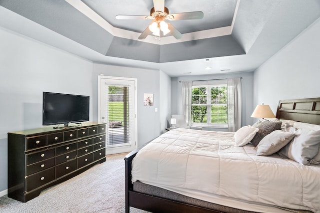 bedroom featuring a ceiling fan, access to outside, light carpet, and a tray ceiling