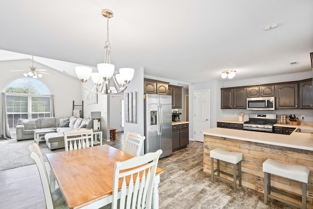 dining room featuring light wood-style floors, ceiling fan with notable chandelier, and lofted ceiling