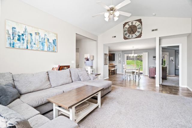 carpeted living room with visible vents, baseboards, ceiling fan with notable chandelier, and high vaulted ceiling