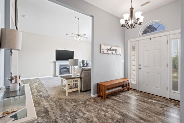 foyer entrance with high vaulted ceiling, ceiling fan with notable chandelier, baseboards, wood finished floors, and visible vents