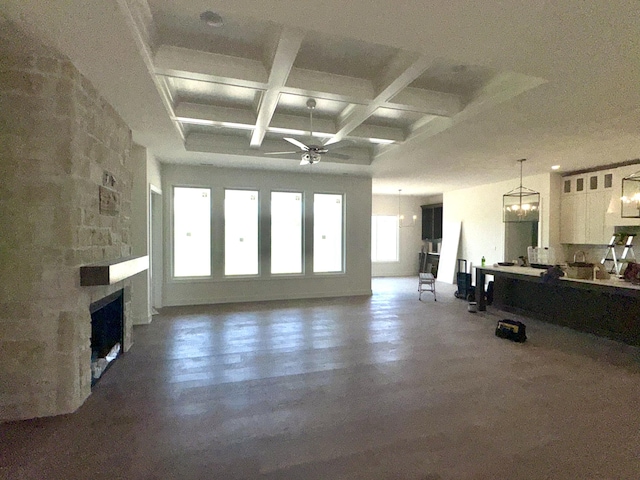living room featuring ceiling fan, a stone fireplace, beamed ceiling, and coffered ceiling