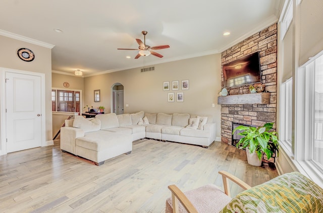 4716 Emeribrook Ct, Columbia, MO 65203 - living room with visible vents, arched walkways, a ceiling fan, a fireplace, and light wood-style flooring