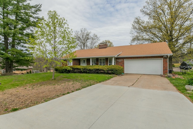 single story home featuring a chimney, driveway, brick siding, a front yard, and a garage
