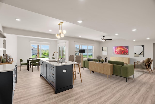 kitchen featuring a sink, light countertops, light wood-style floors, and a breakfast bar area