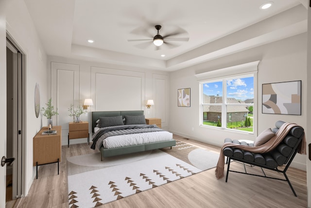 bedroom with recessed lighting, baseboards, a raised ceiling, and light wood-style floors