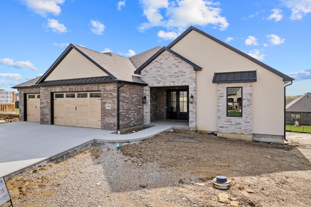 view of front of house with a garage, a standing seam roof, concrete driveway, and stone siding