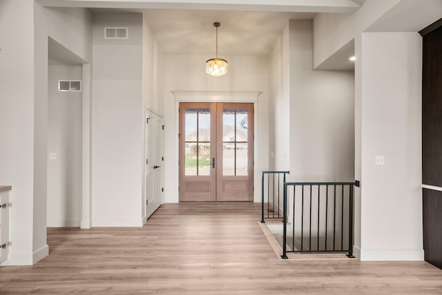 doorway with french doors, visible vents, baseboards, light wood finished floors, and an inviting chandelier