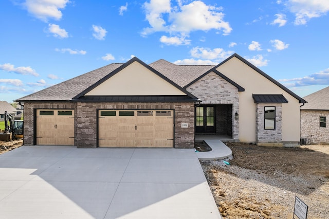 view of front of house with roof with shingles, a standing seam roof, brick siding, an attached garage, and driveway