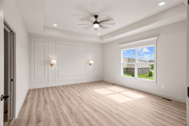 unfurnished bedroom featuring a raised ceiling, baseboards, light wood finished floors, and visible vents