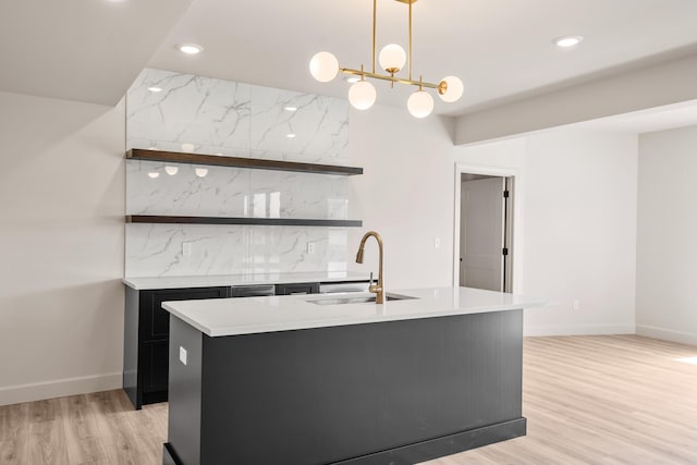 kitchen with a sink, light wood-style floors, light countertops, dark cabinets, and recessed lighting