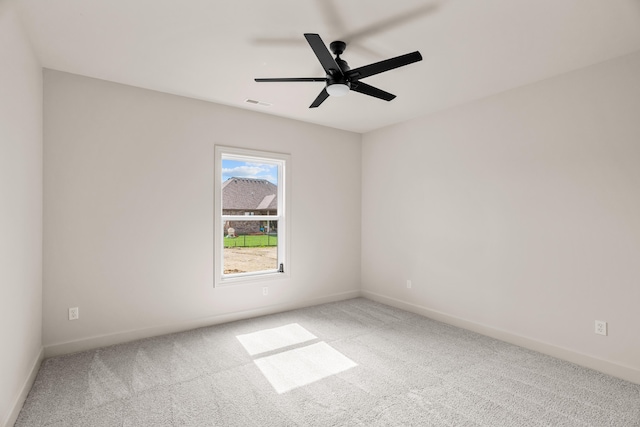 carpeted empty room with baseboards, ceiling fan, and visible vents