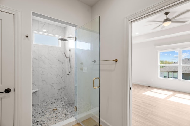 full bathroom featuring ceiling fan, a marble finish shower, baseboards, and wood finished floors