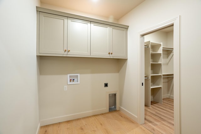 washroom featuring light wood-style floors, hookup for a washing machine, baseboards, cabinet space, and hookup for an electric dryer
